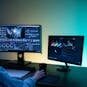 A video editor works on dual monitors in a modern setup, focusing on color grading and editing visuals.